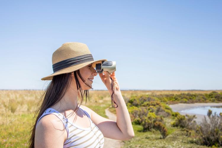 Woman using binoculars at wetlands